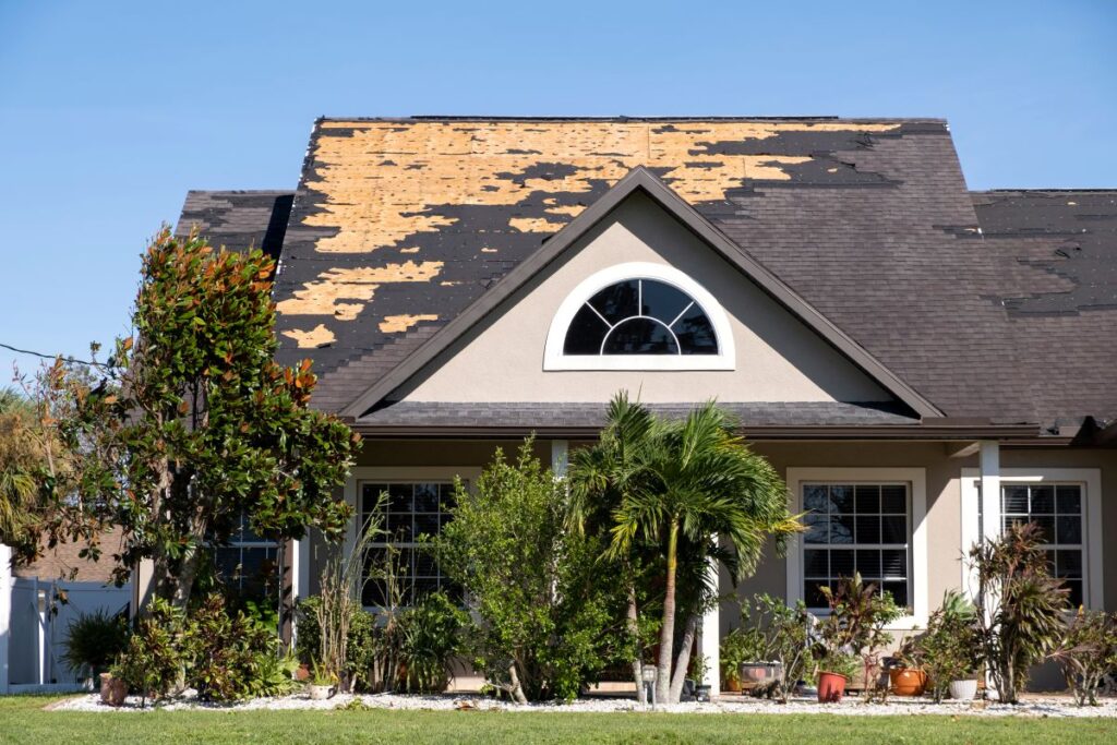 Wind damaged house roof with missing asphalt shingles