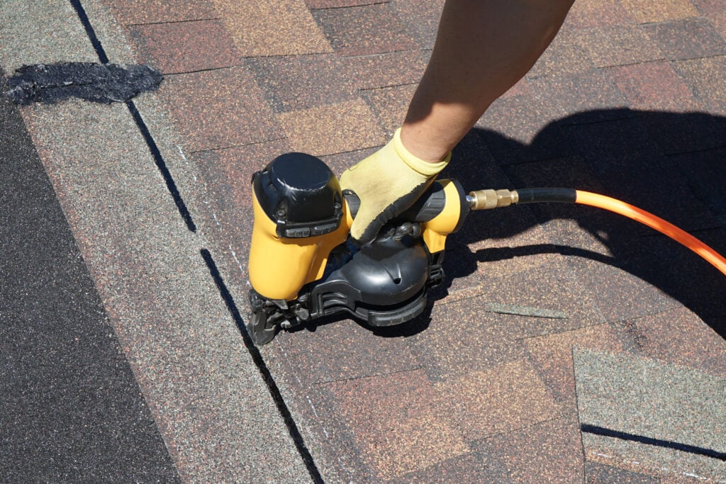 best roofing shingles A new roof cover protection being applied. A roofer nailing shingles with air gun.