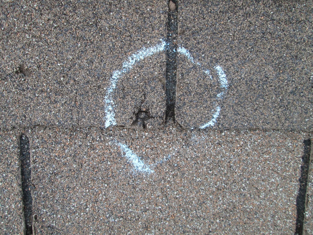 hail damage roof repair shingle marked with white chalk