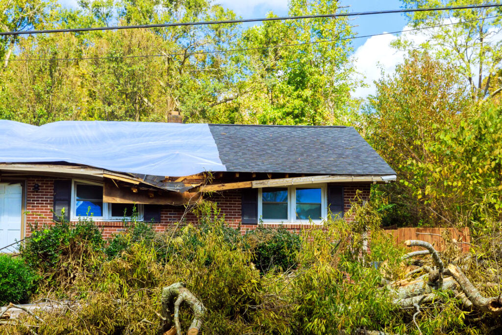 Storm damage shows fallen trees roof repairs on house in suburban area